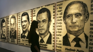 A woman looks at pictures depicting Russia's Vladimir Putin and Dmitry Medvedev during the Moscow Fine Art Fair