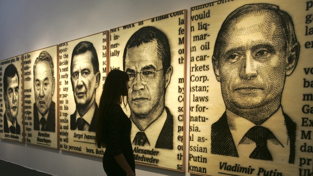 A woman looks at pictures depicting Russia's Vladimir Putin and Dmitry Medvedev during the Moscow Fine Art Fair