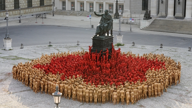 Volunteers painted in red and gold pose for US photographer Spencer Tunick in Munich