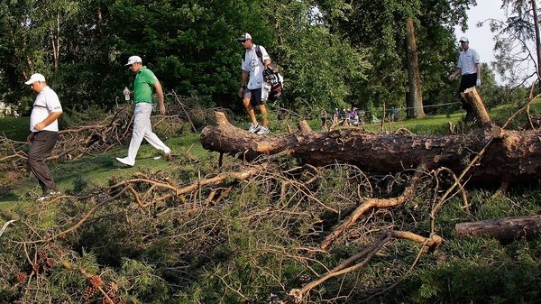 Brendon de Jonge of Zimbabwe (l) and Hunter Mahan (c) walk past debris from an overnight storm