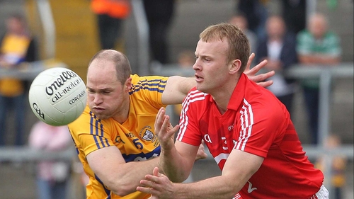 Cork's Michael Shields gets his handpass away despite the best efforts of Michael O'Shea of Clare