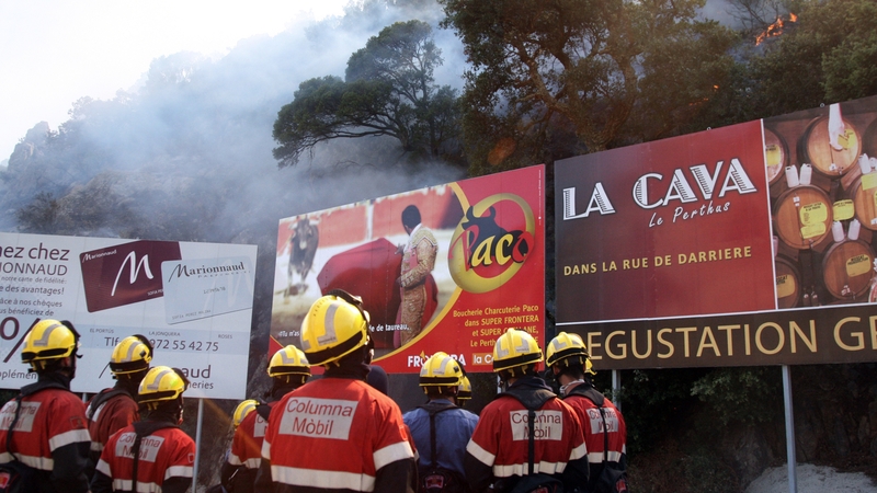 Firefighters watch smoke rising from the forest