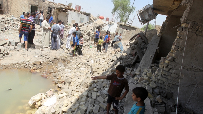 Iraqis stand in the rubble of destroyed houses following a series of bomb attacks in the town of Taji