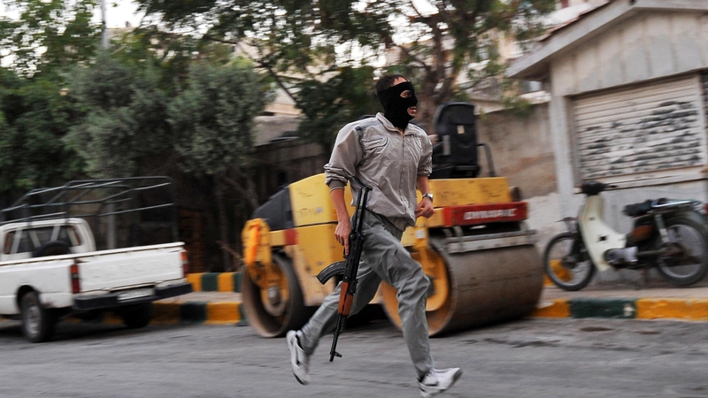 A Syrian rebel runs in a street of Selehattin, near Aleppo, during an attack on the municipal building