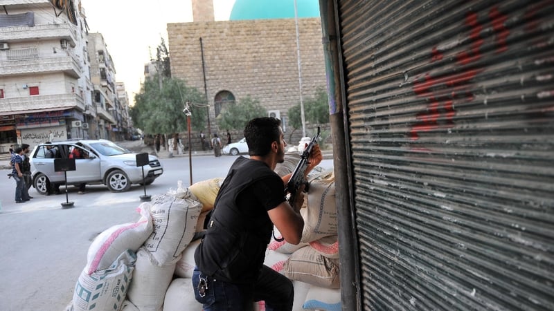 A Syrian rebel takes position as a helicopter hovers over the northern city of Aleppo