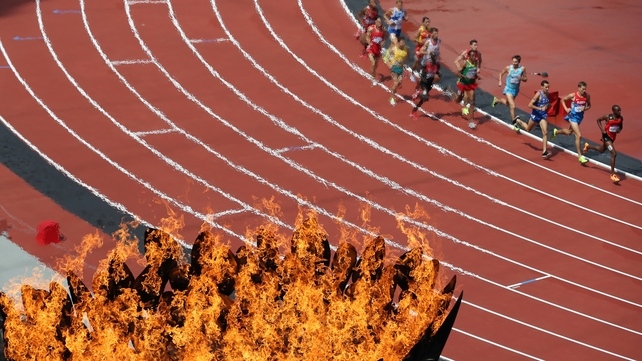 The Olympic flame burns as athletes compete in the heats of the men's 3000m steeplechase