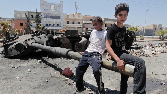 Boys sit on a destroyed Syrian army tank after a battle in the city of Aleppo