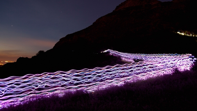 Runners and walkers dressed in light emitting suits and holding light sticks make their way up Arthur's Seat as part of the Edinburgh Festival