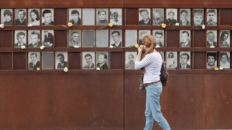 A woman looks at portraits of people killed at the Berlin Wall on the 51st anniversary of its construction
