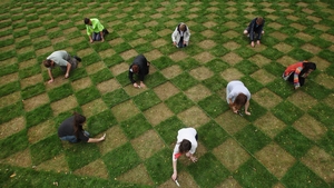 Volunteers cut a checkerboard design in the lawn at the National Trust's Ham House and Garden as part of an art project by Caroline Wright