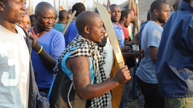 A miner holds up a machete as he takes part in a strike calling for increased wages at a platinum mine in Marikana, South Africa