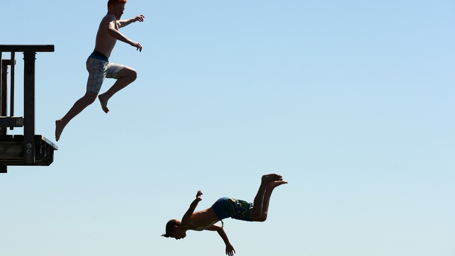 Boys jump from the diving platform of the lido at the lake Ammersee near the small village of Utting in southern Germany