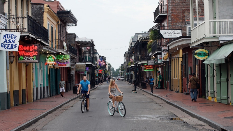 People ride bicycles down a virtually empty Bourbon street in New Orleans