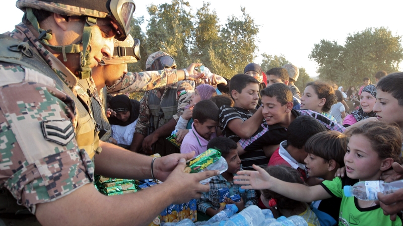 Jordanian soldiers distribute water and snacks to newly-arrived Syrian refugees after they crossed the border into Jordan