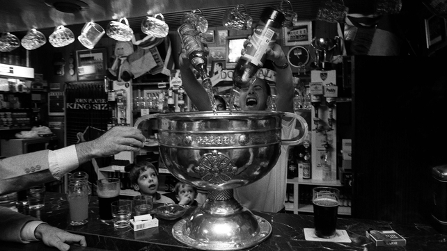 A barman fills the Sam Maguire with what looks to be whiskey and red lemonade