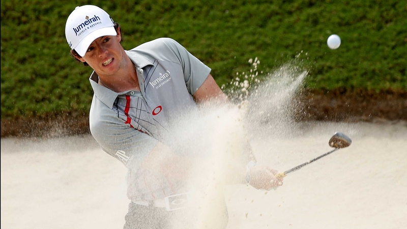 Rory McIlroy plays a bunker shot on the first hole