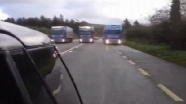 The footage shows articulated lorries driving abreast of each other across both sides of a single-carriageway road
