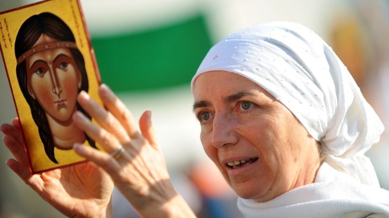 A mass-goer hold a portrait of Kateri Tekakwitha