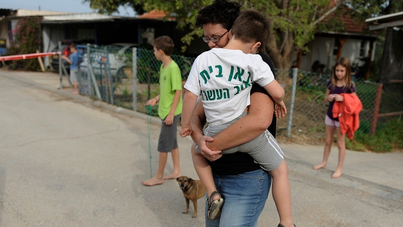 An Israeli mother carries her child following a rocket attack from Gaza