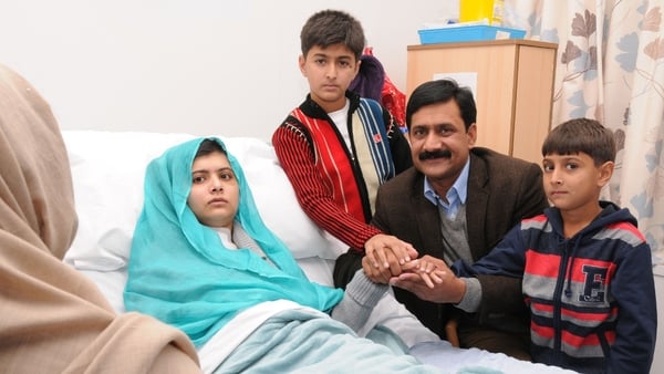 Malala Yousafzai sits up in her hospital bed with her father Ziauddin and her two younger brothers, Atal Khan (R) and Khushal Khan (C)