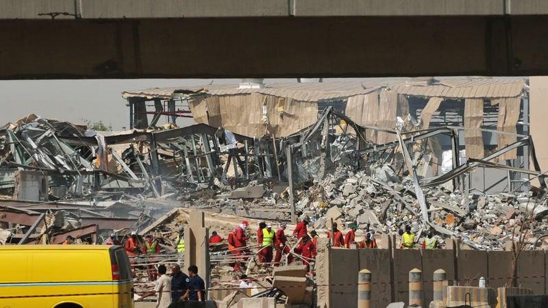 A destroyed factory is seen in the background as Saudi rescuers inspect the site