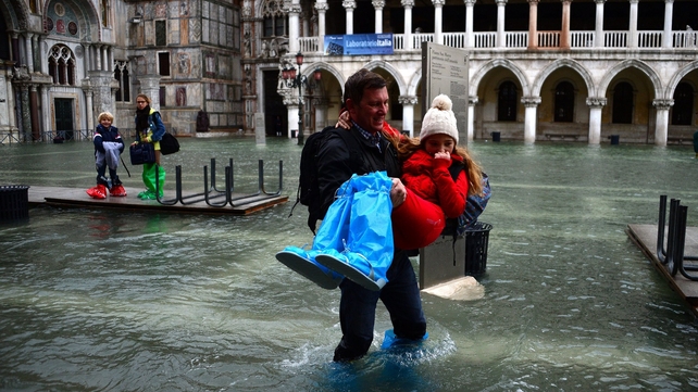 A man carries a girl as they leave the flooded St Mark's Square in Venice during 'acqua alta' (high water)