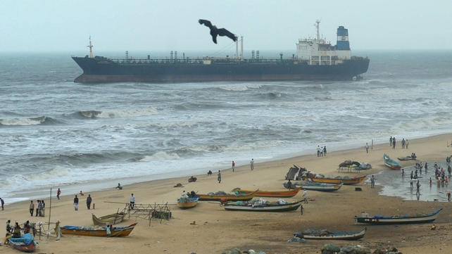 Indian fishing boats rest on a beach near the oil tanker ship Pratibha Cauvery after the ship ran aground 31 October off the coast in Chennai