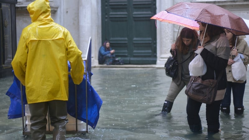 People walk in a flooded street during a 'acqua alta' in Venice