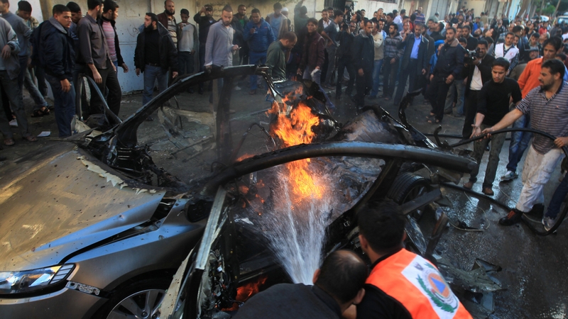 Palestinian firefighters extinguish fire from the car of Ahmaed Jaabari