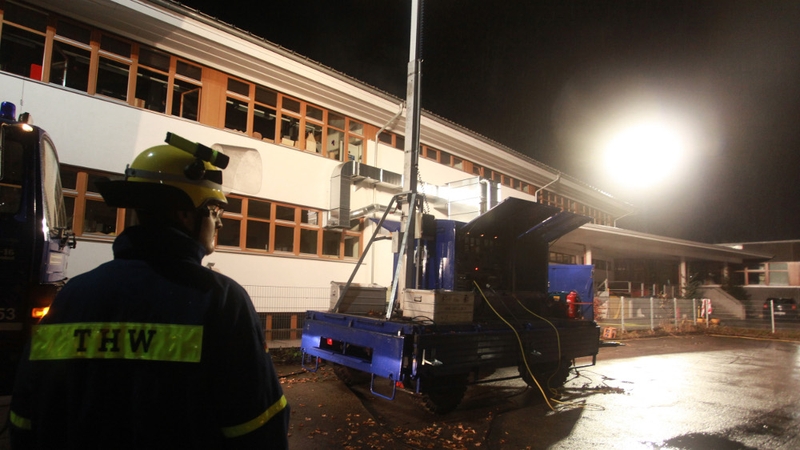 A member of the German Federal Agency for Technical Relief stands outside the charred facility