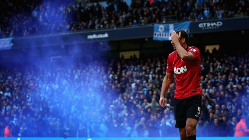 Rio Ferdinand reacts after being struck by an object thrown from the crowd