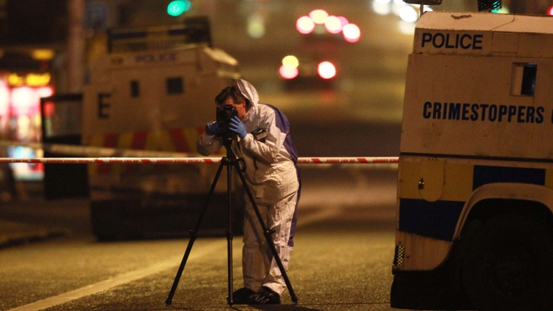 A forensics photographer photographs a burnt police patrol car outside Alliance Party MP Naomi Long's office in east Belfast