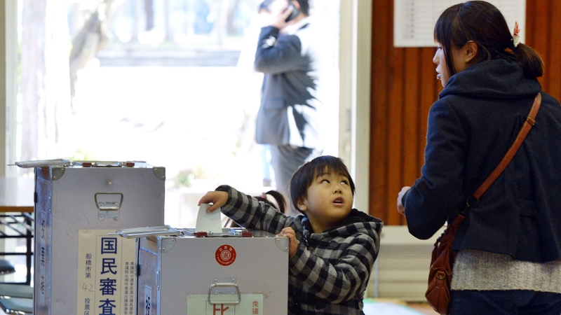 A boy helps his mother to cast a vote at a polling station in Funabashi, suburban Tokyo