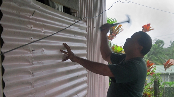 Local resident Aisea Latu nails a sheet of corrugated metal onto the shutters of his house on Laucala Bay Road, Suva