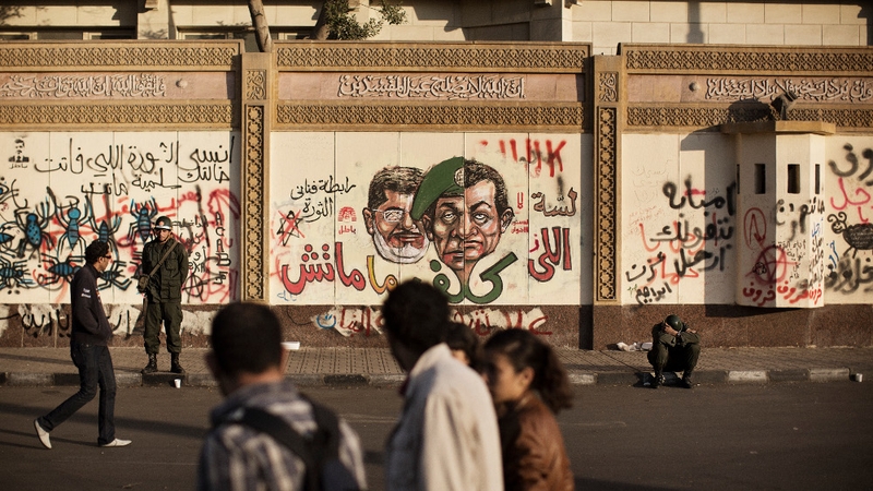 A group of Egyptian students walk past Egyptian soldiers securing the area of the President's Palace in Cairo