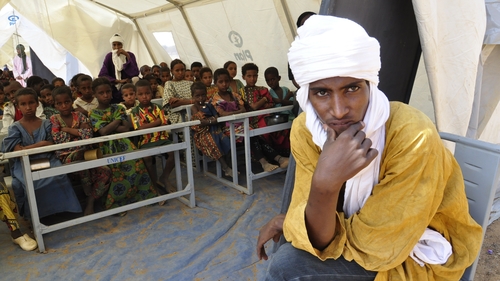 Malian refugee children sit under a tent that serves as a classroom in the Goudebou refugee camp near the city of Dori
