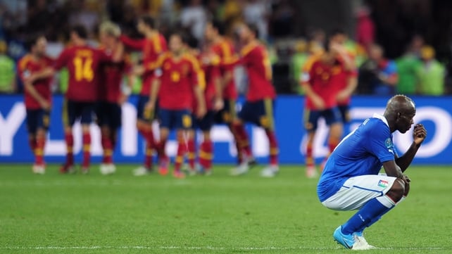 A dejected Mario Balotelli can't watch as Spain celebrate winning the Euro 2012 final against Italy
