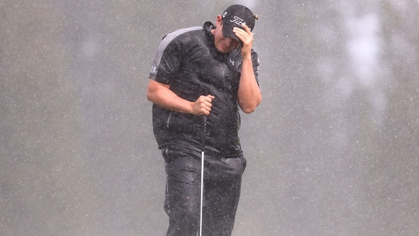 Scott Stallings shields himself from the wind and rain during the opening round