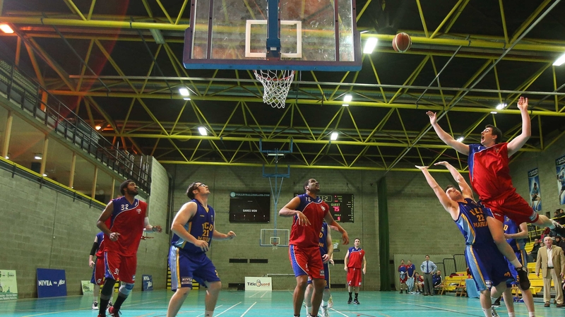 Ciaran O'Sullivan of UCC Demons shoots the winning basket while under pressure from Cathal Finn of UCD Marian