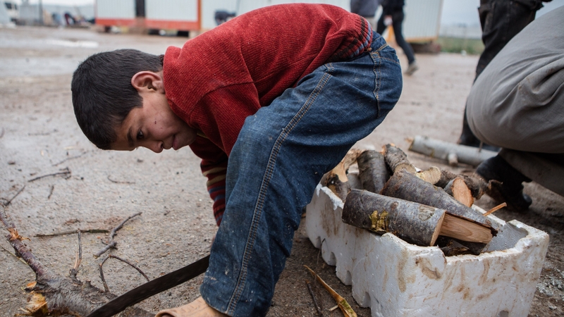 A Syrian boy cuts wood at a refugee camp near the city of Azaz on the Syria-Turkey border, home to more than 7,000 people
