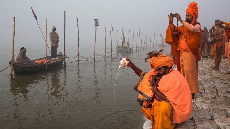 A Sadhu, Hindu holy man, pours water from a conch shell as he prays on the banks of the Ganges