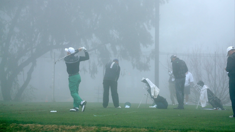 Players hit balls on the practice range during a fog delay