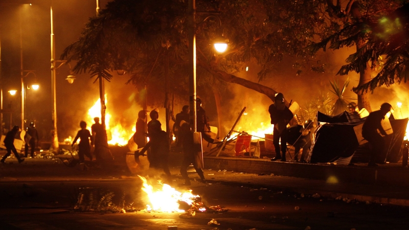 Egyptian riot policemen set fire to the tents of the protesters in front of the gate of the presidential palace in Cairo