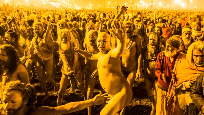 Hindu holy men walk in procession to bathe on the banks of Sangam