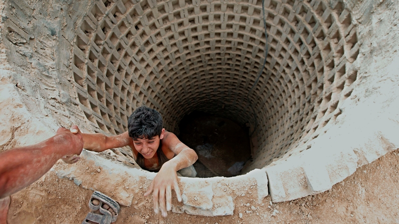 A Palestinian man helps a smuggler to ascend a tunnel along the Gaza-Egypt border in Rafah, in southern Gaza