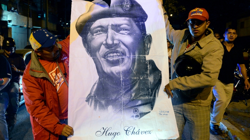 Supporters carry a poster of Hugo Chavez after learning of his death