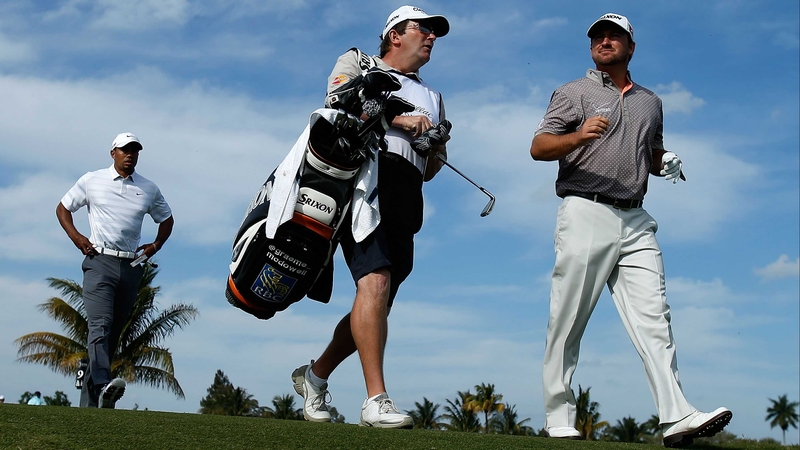 Graeme McDowell walks alongside his caddie Ken Comboy as Tiger Woods follows