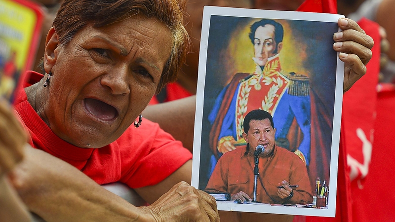 A supporter holds a picture showing Venezuelan hero Simon Bolivar and Hugo Chavez