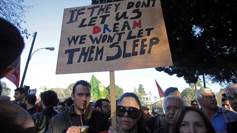 A Cypriot demonstrator holds a banner during a protest against a EU bailout deal outside parliament