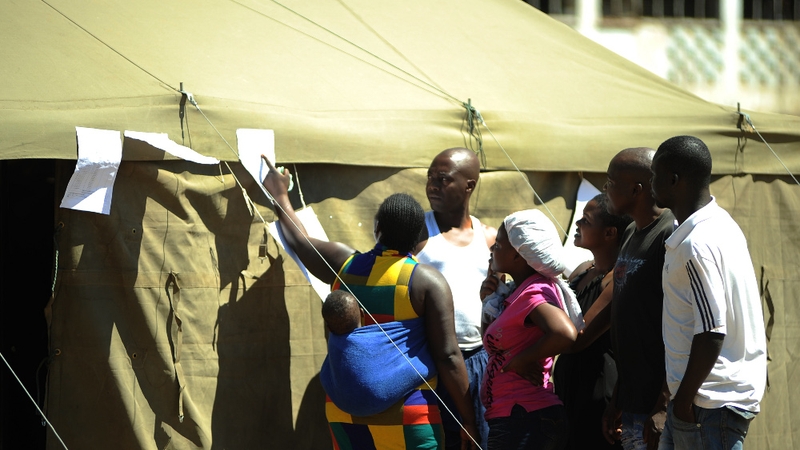 People check for results outside a polling station in Mbare township after voting for a new constitution